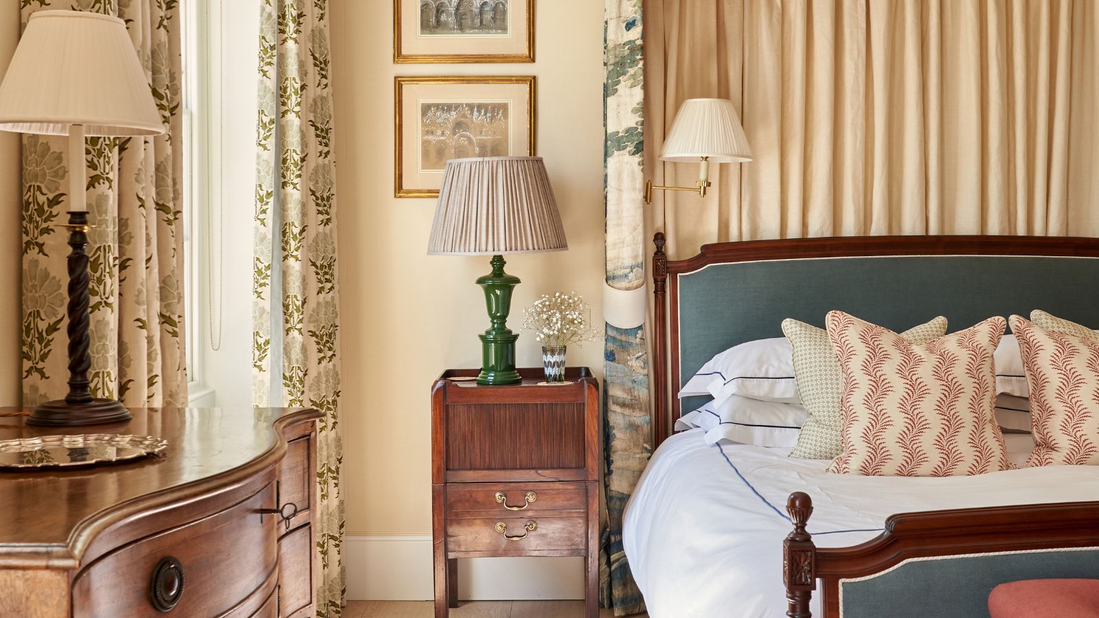 Vintage-Schlafzimmer mit bedruckten Vorhängen, Beistelltisch aus Holz, Vintage-Lampen und Holzrahmenbett mit Baldachin