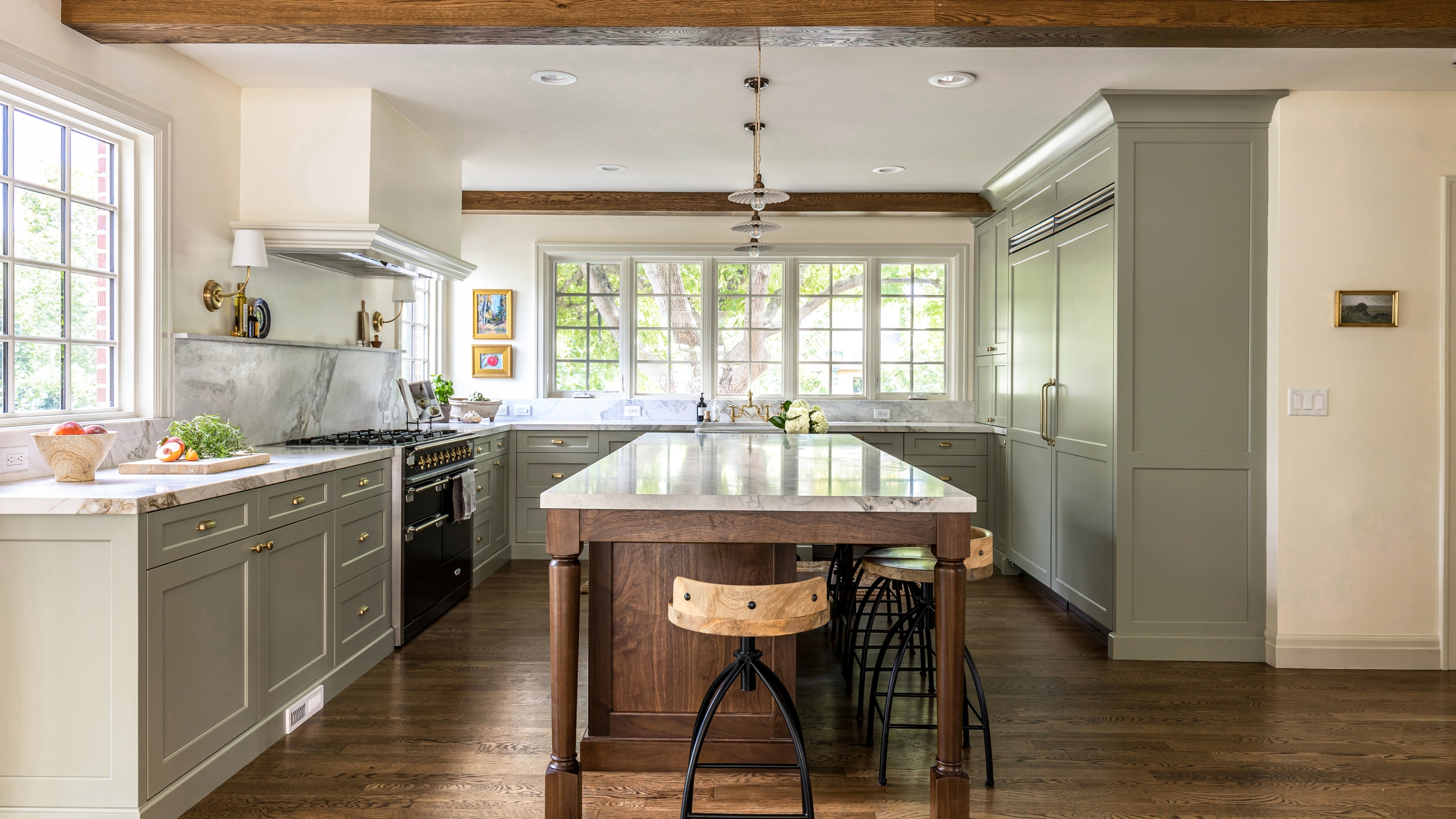 Eine U-förmige Küche mit von Farrow and Ball in French Grey lackierten Schränken, Marmorarbeitsplatten, Messingbeschlägen und einer Holzinsel