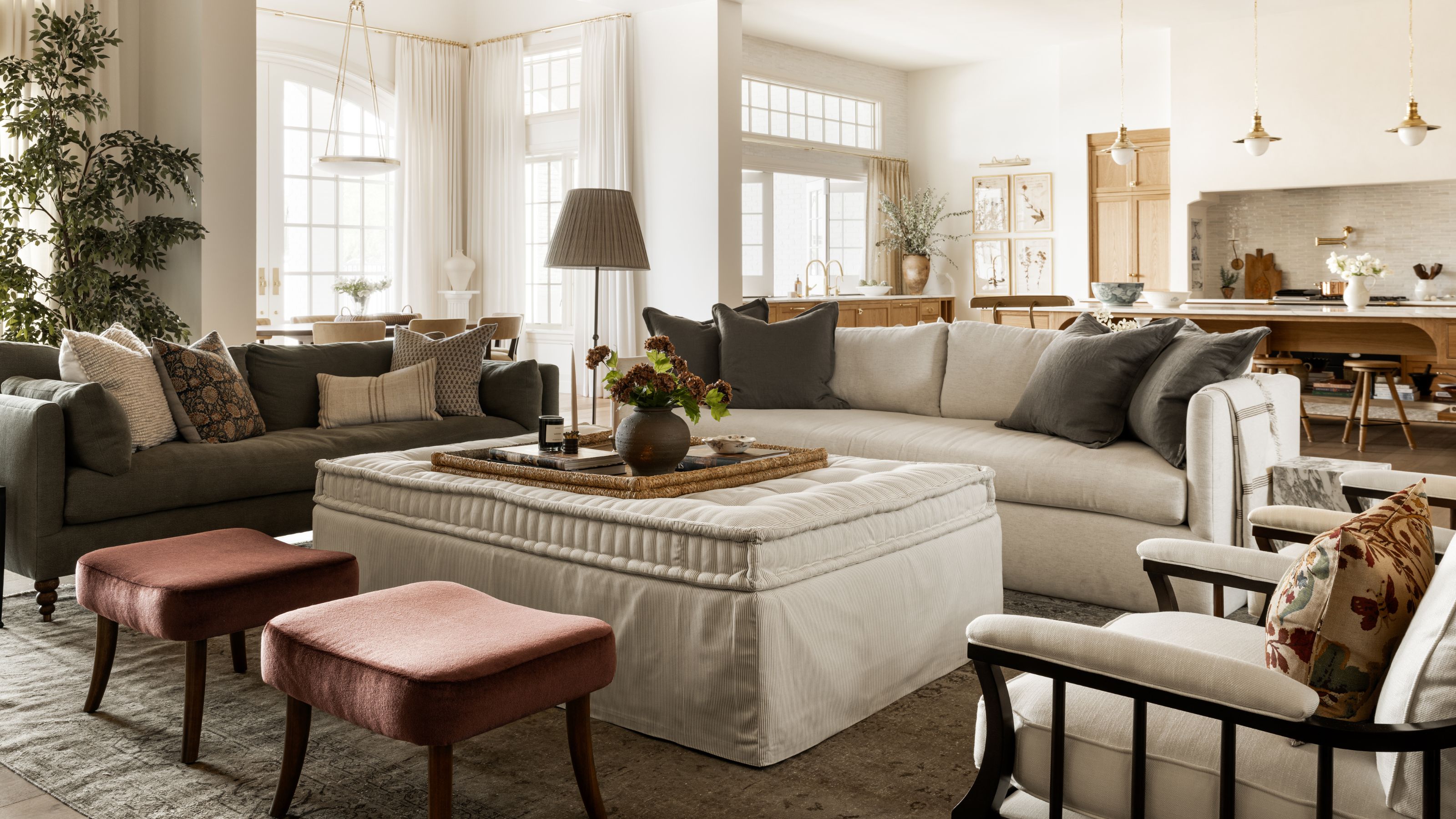 ein großer offener Wohn- und Küchenbereich mit großer neutraler Couch, Leinenhocker, rostroten Hockern und dunkelgrüngrauen Akzenten