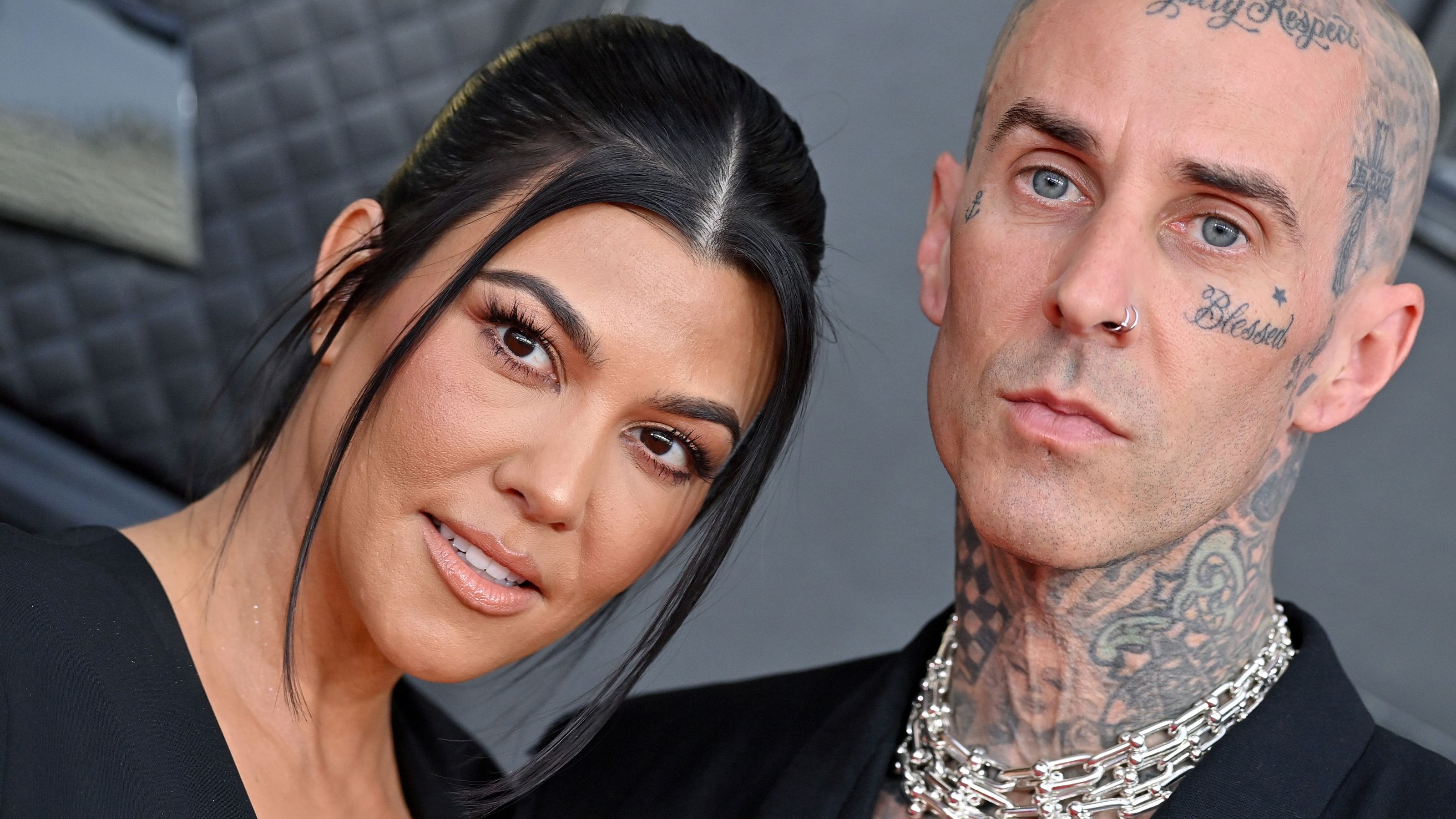 Travis Barker und Kourtney Kardashian auf grauem Hintergrund