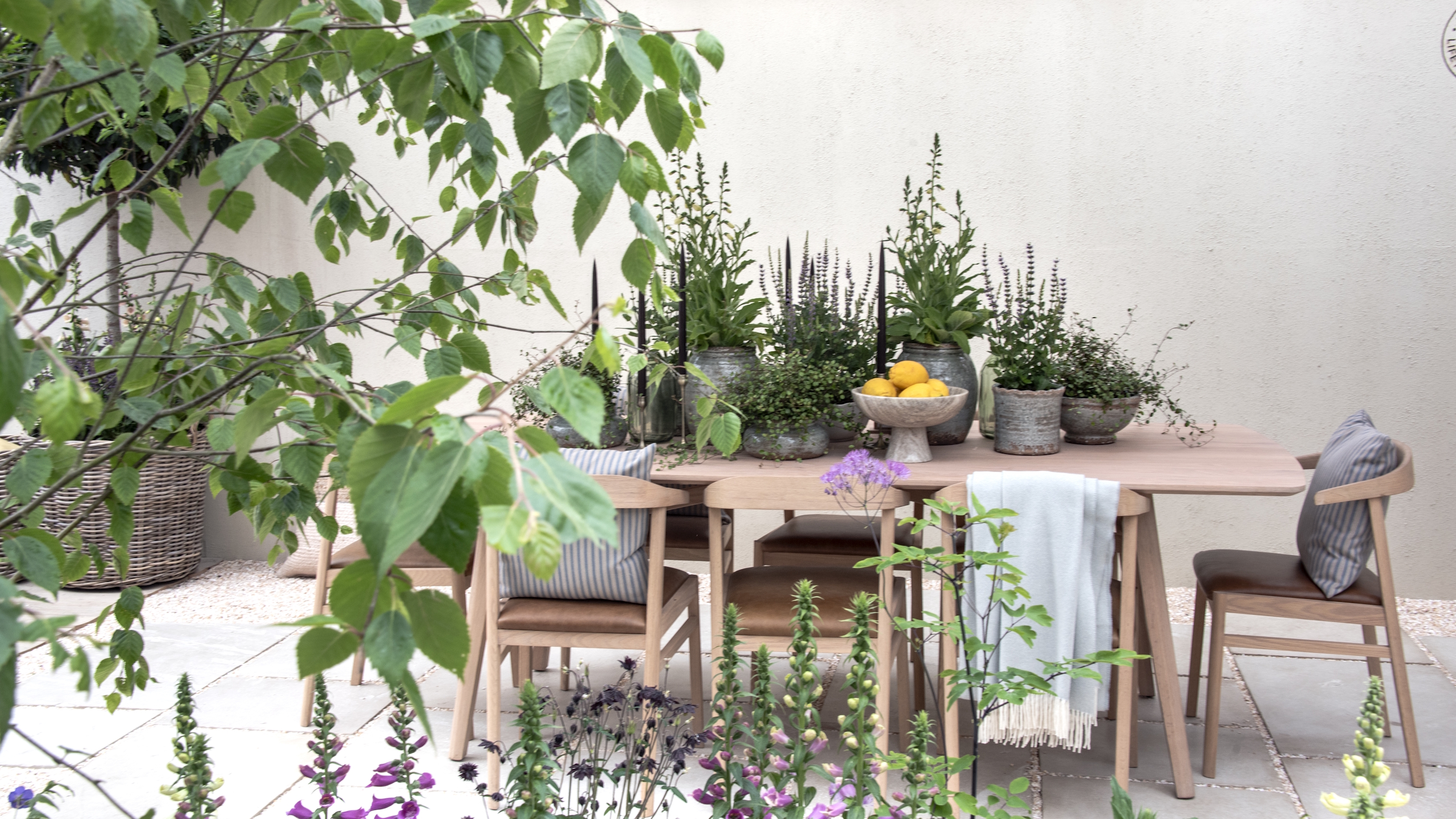Ein Holztisch und Stühle mit Topfpflanzen auf einem Schaugarten der RHS Chelsea Flower Show