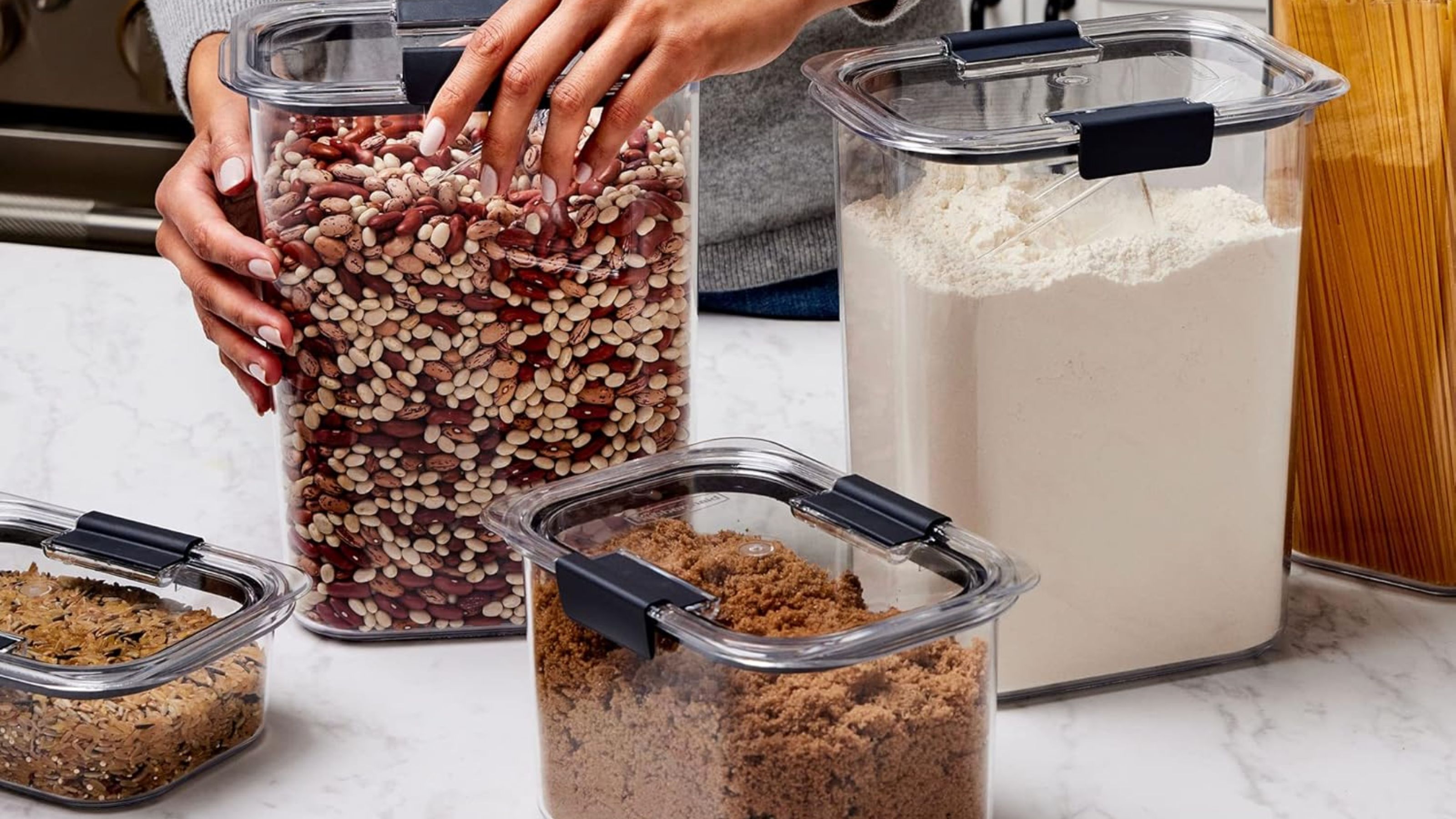 Ein Satz Rubbermaid Brilliance-Behälter auf einer Küchentheke aus Marmor, gefüllt mit getrockneten Vorratsprodukten
