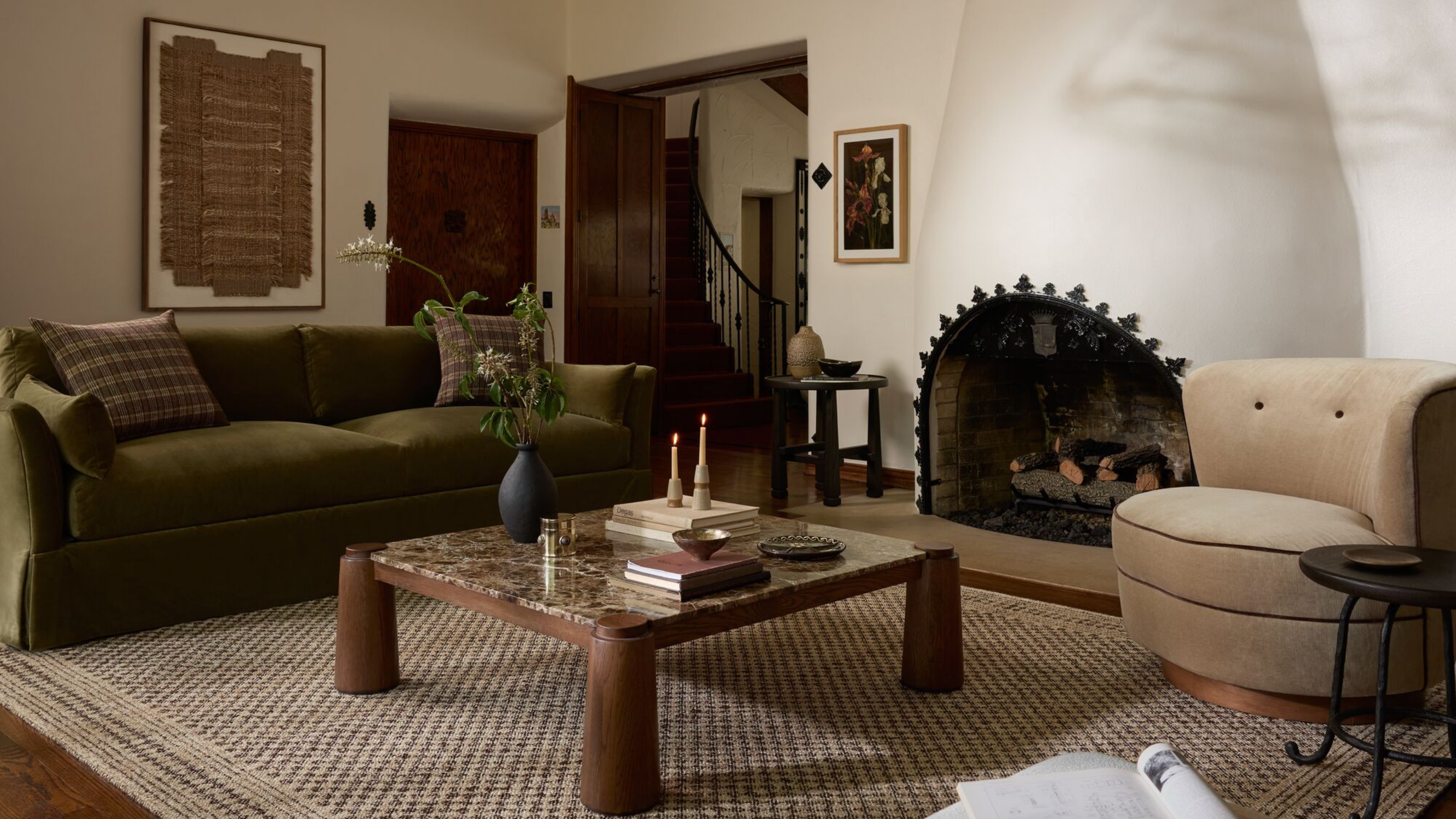 ein gemütliches Wohnzimmer mit einem großen Kamin, einem Couchtisch aus Holz und Marmor, einer grünen Couch und einem hellbraunen Drehstuhl