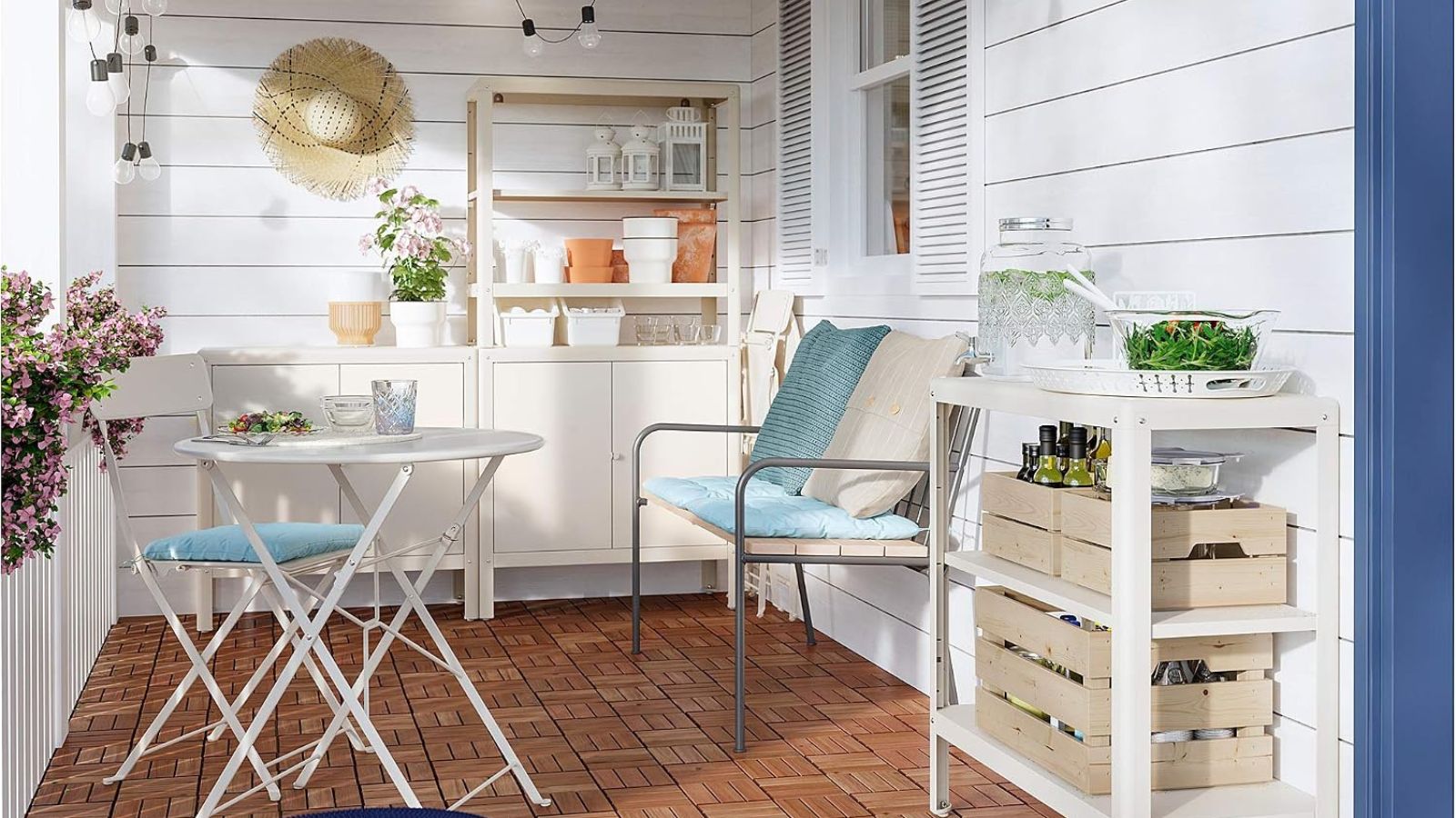 Eine kleine Terrasse mit cremefarbenem IKEA-Außenlager und einem weißen Bistro-Set mit blauen Kissen