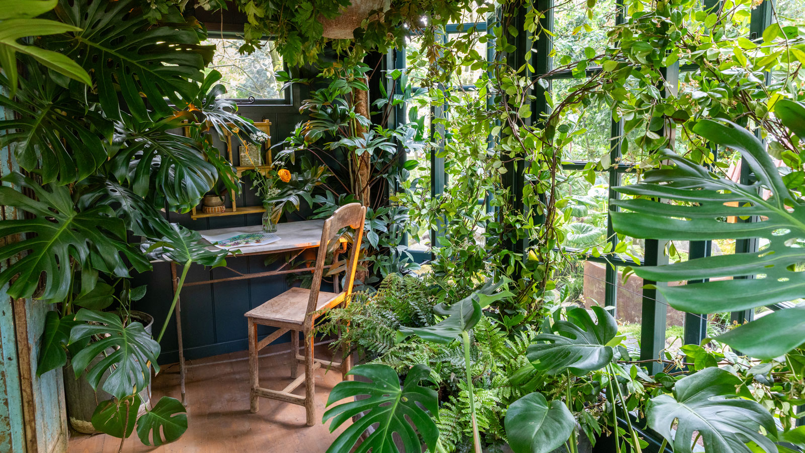 Biophiles Innendesign mit Zimmerpflanzen wie Monstera und Farnen, mit Liege und Stuhl