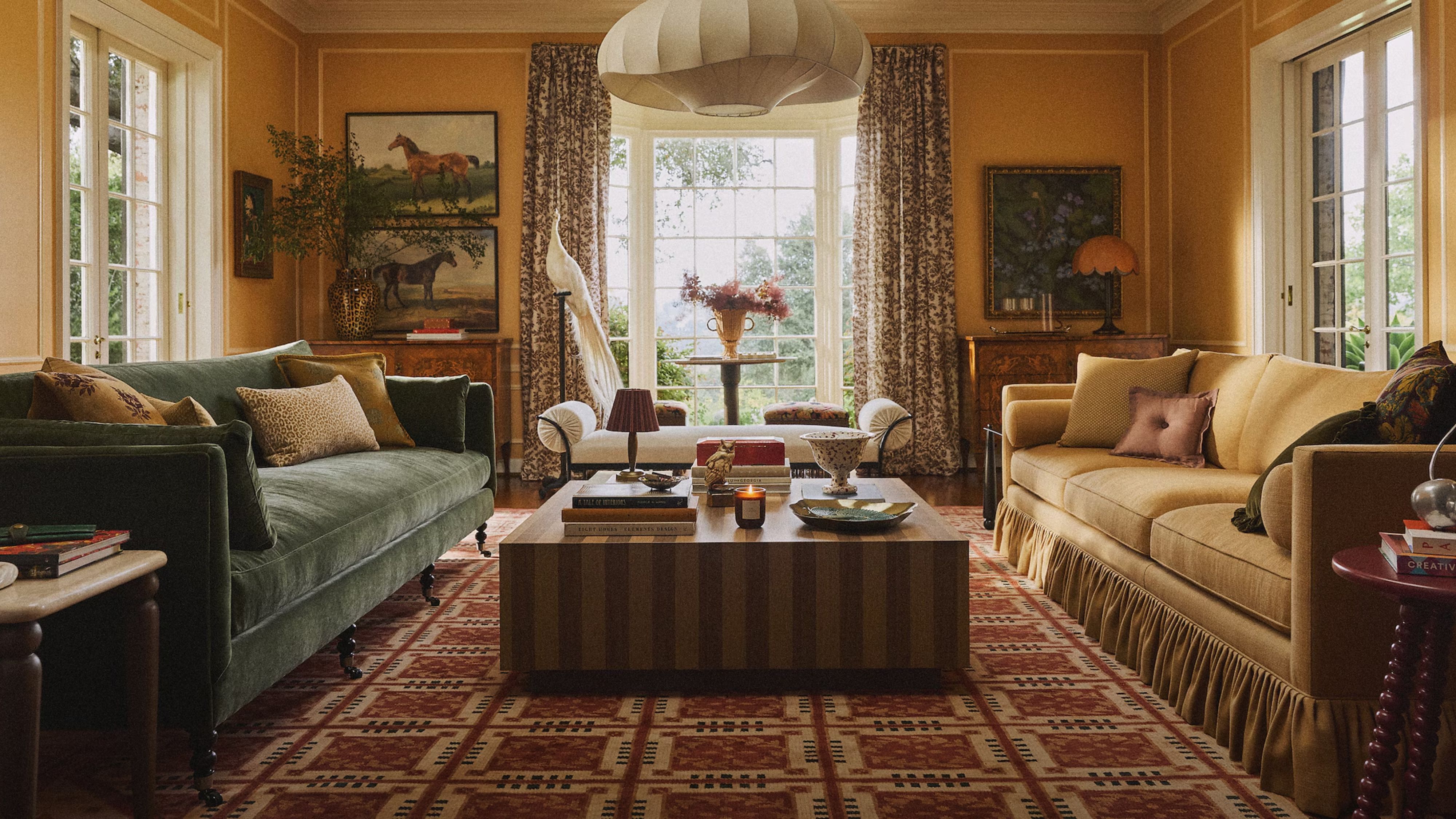 Reichhaltig gestaltetes Herbstwohnzimmer mit juwelenfarbenen Sofas, einem gestreiften Couchtisch, Reiter-Wandkunst und mehreren tragbaren Lampen.