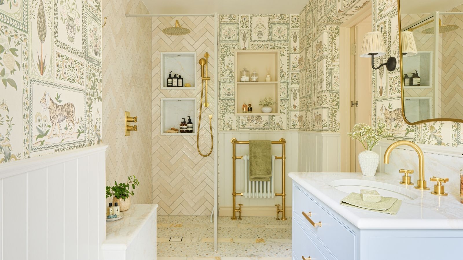 A large shower room with tiger-themed wallpaper, a glass shoer screen, pink shower tiles, and brass fixtures