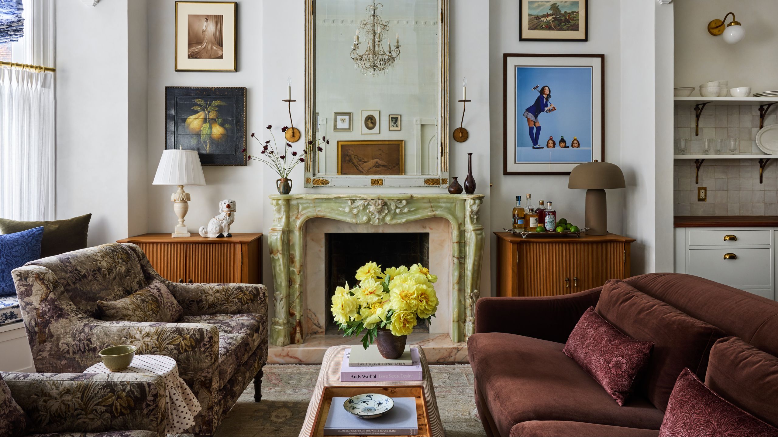 Ein mehrschichtiges Vintage-Wohnzimmer in einem New Yorker Apartment mit grünem Marmorkamin, Holzkavitetten in den Nischen und vielseitigen Kunstwerken