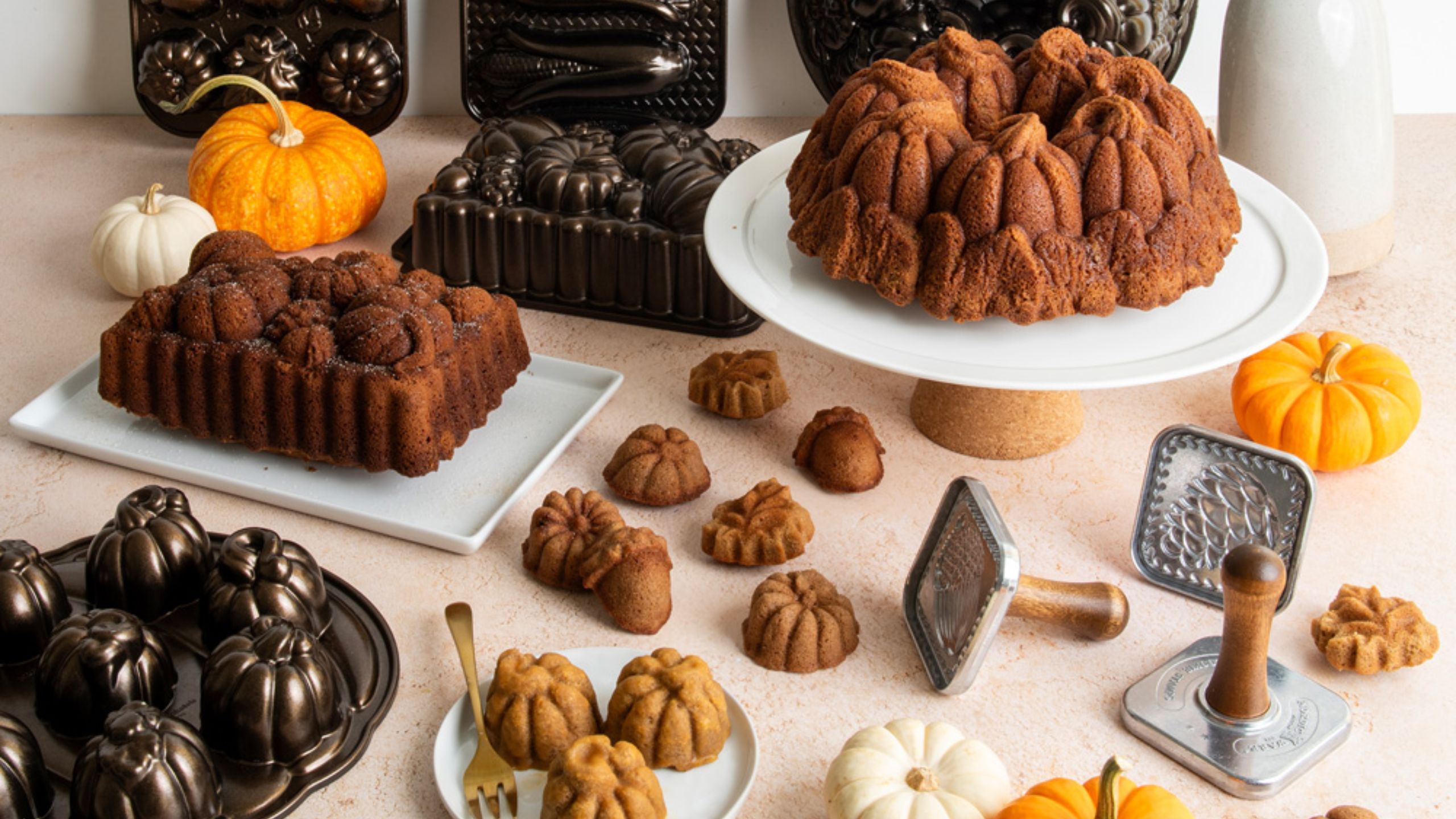 Eine Auswahl an Herbstbackformen von NordicWare, umgeben von Kuchen. 