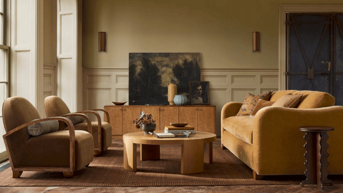 Senffarbenes Sofa und zwei Sessel im neutralen Wohnzimmer mit Couchtisch und Sideboard 