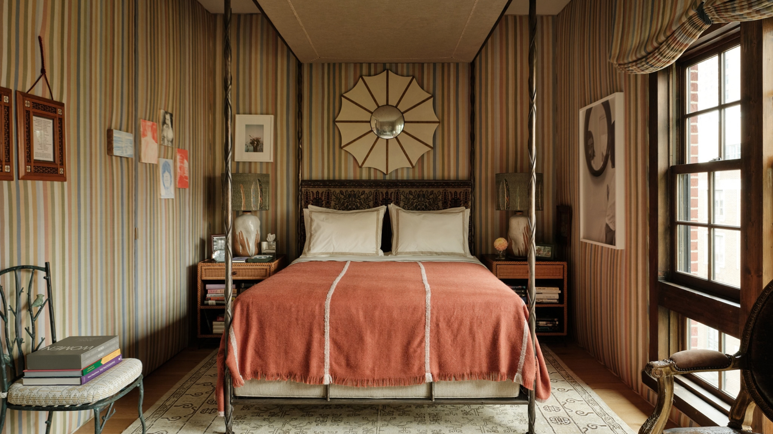 Charaktervolles, gestreiftes Schlafzimmer mit einem Himmelbett mit Himmelbett, eingefassten Kissenbezügen und einer strukturierten Terrakotta-Bettdecke im Vintage-Stil.